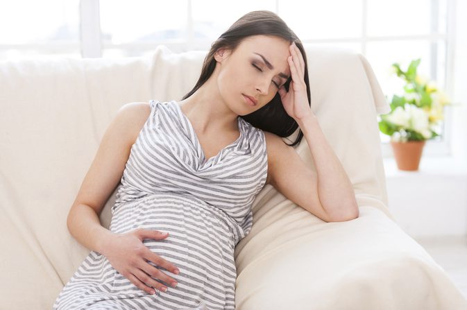 eine schwangere Frau hält sich den Bauch